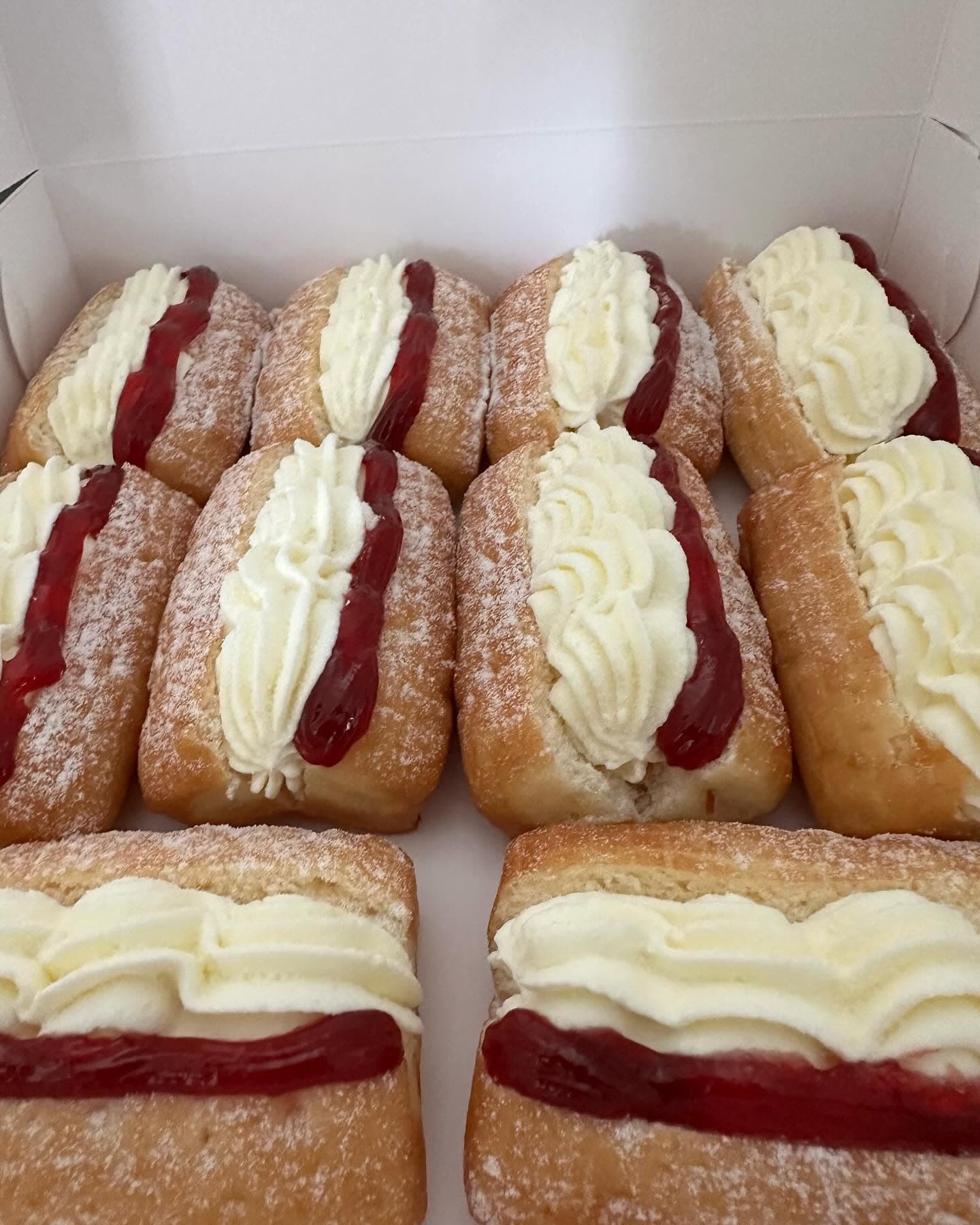Rectangular donuts filled with whipped cream and red jam, dusted with powdered sugar.